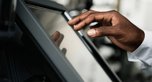 A hand touching a touchscreen point-of-sale system.