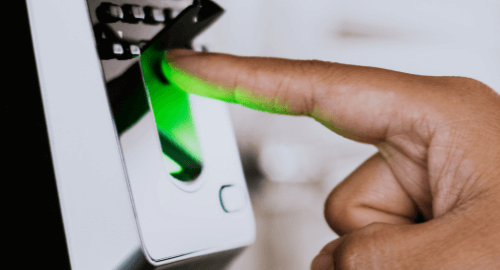 A person's finger scanning on a biometric fingerprint scanner with a green light indicator.