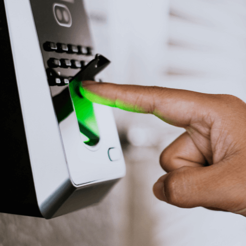 A person's finger scanning on a biometric fingerprint scanner with a green light indicator.